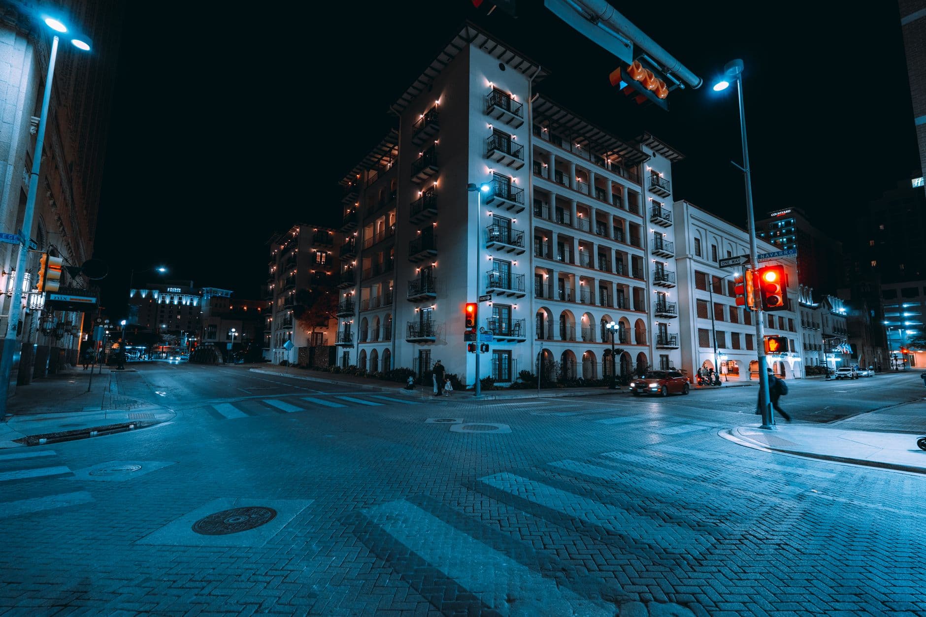 A vibrant night view of a city intersection in downtown San Antonio, Texas.