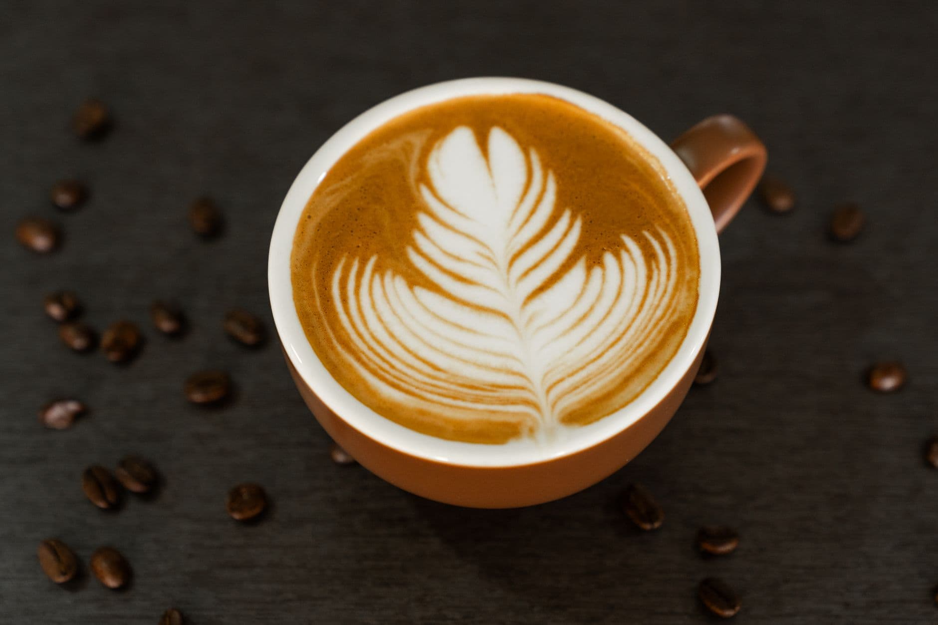 Top view of a cappuccino with intricate latte art on a gray background in Pokhara, Nepal.