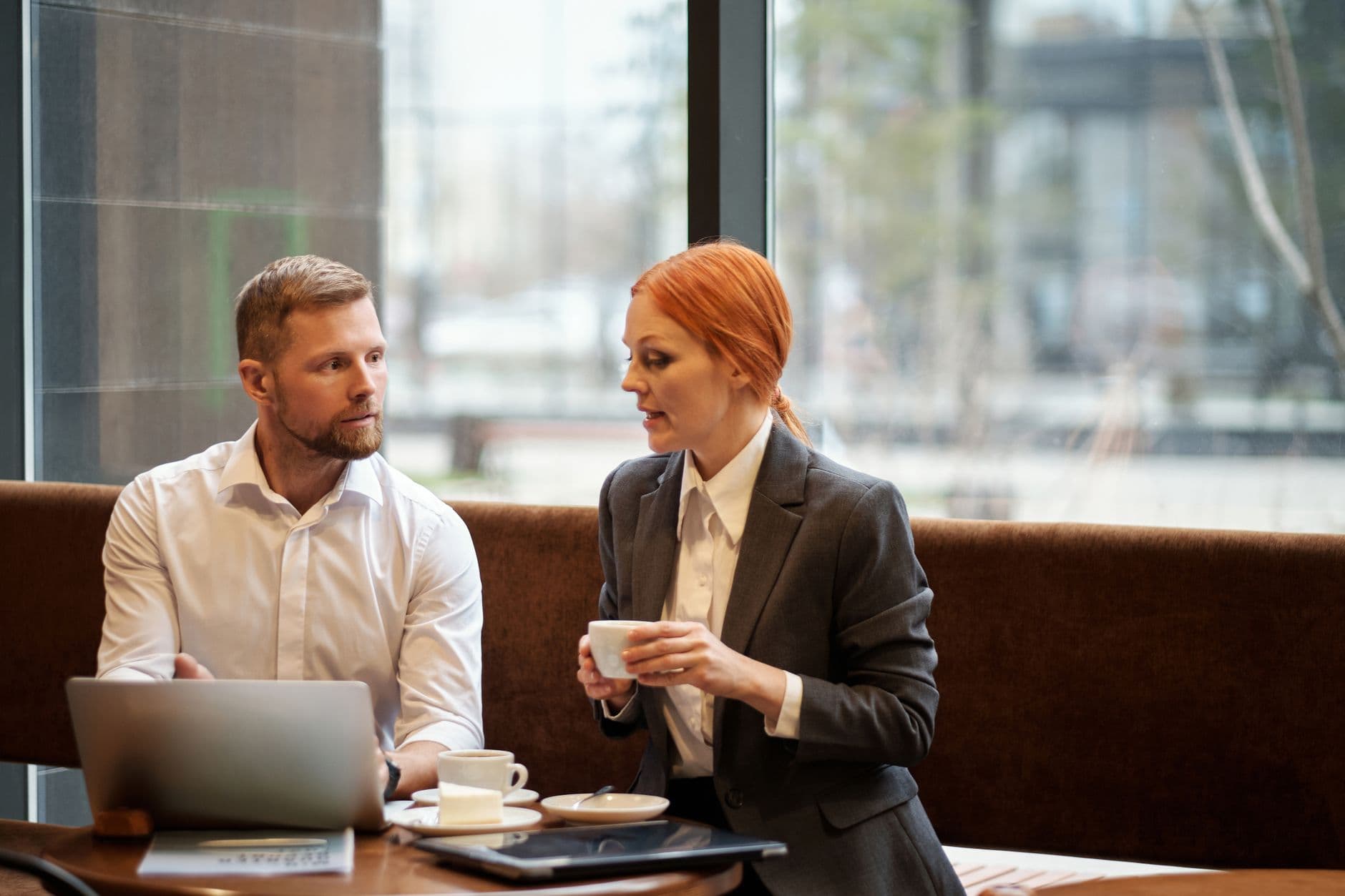 Professional man and woman having a focused discussion over coffee in a modern cafe setting.