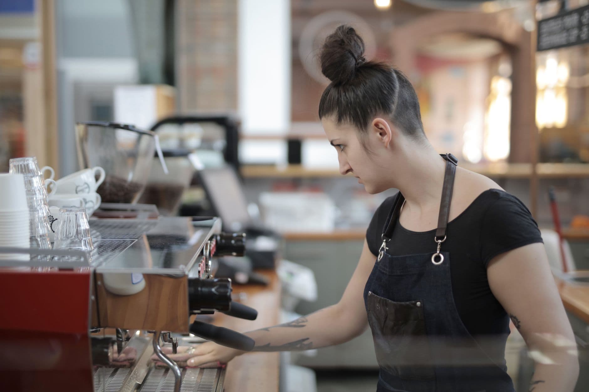 A barista expertly makes coffee at a modern café, using an espresso machine.