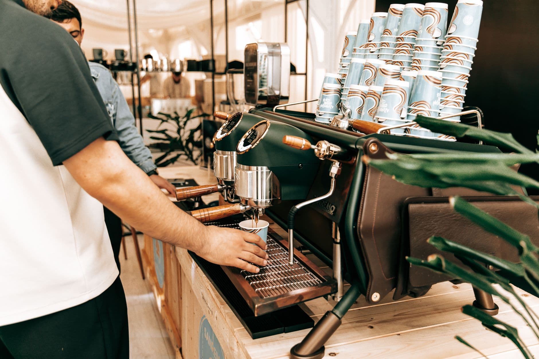 Busy café with baristas preparing coffee in Baku, Azerbaijan using an espresso machine.
