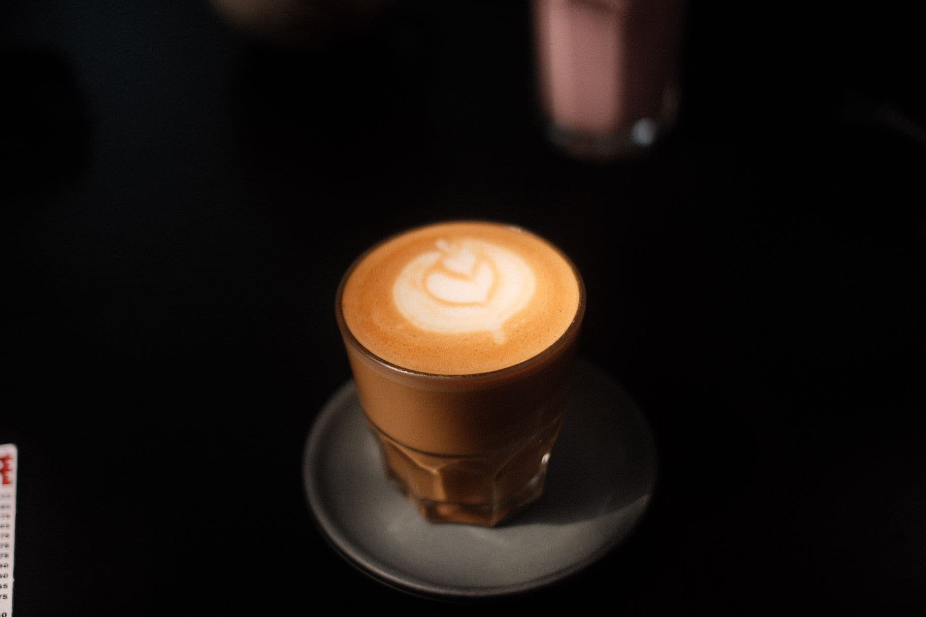 A beautifully crafted latte with intricate foam art in a dimly lit setting.