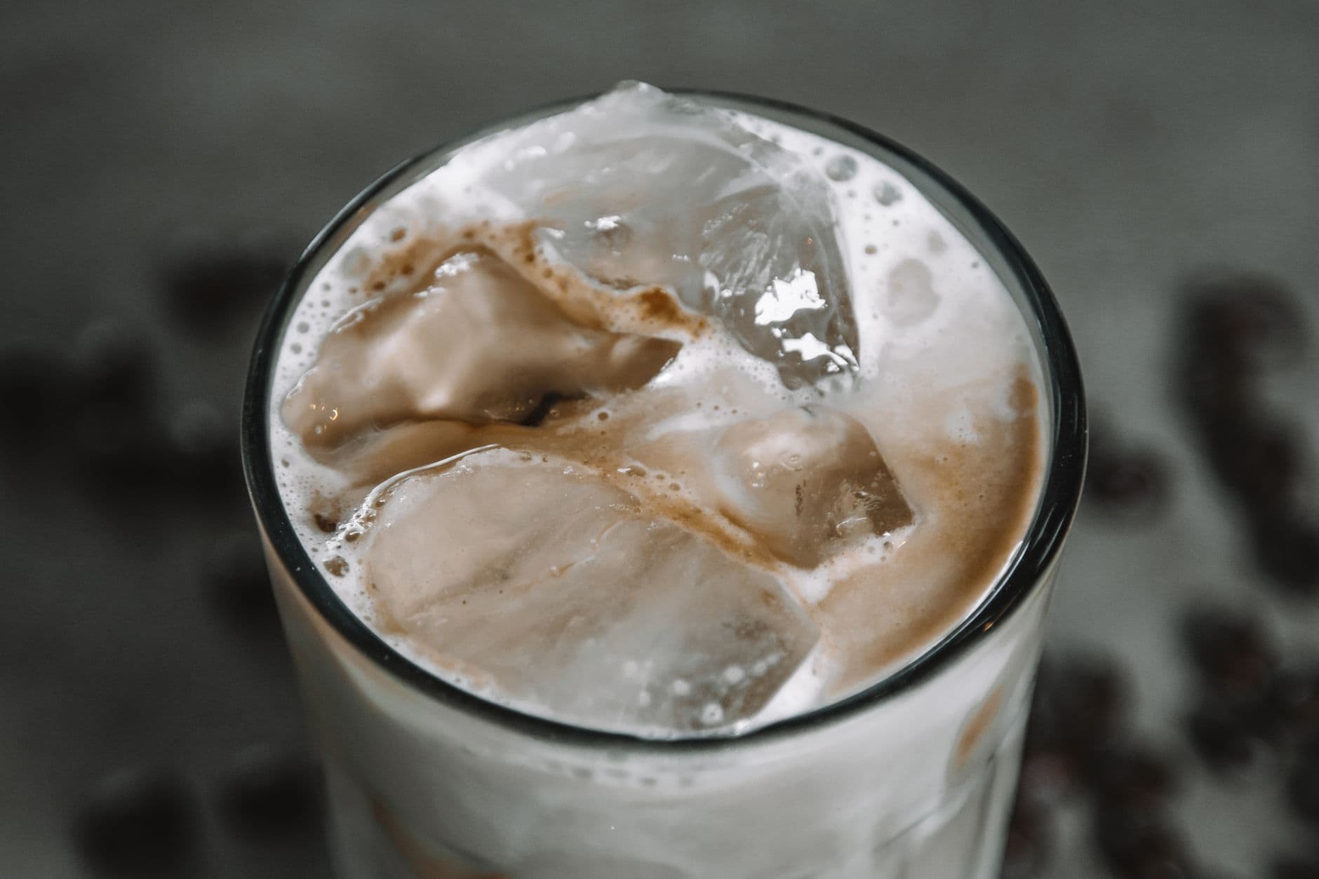 Refreshing iced coffee topped with creamy foam and ice cubes in a glass.