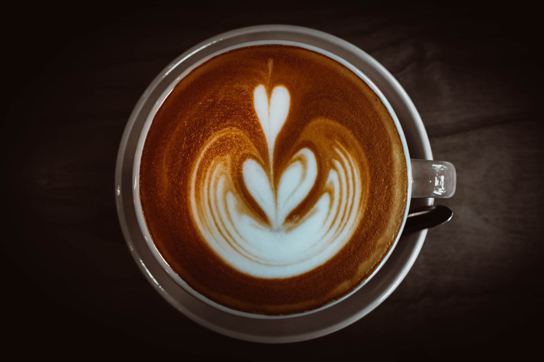 Top view of a cappuccino featuring elegant heart-shaped latte art in a ceramic cup.