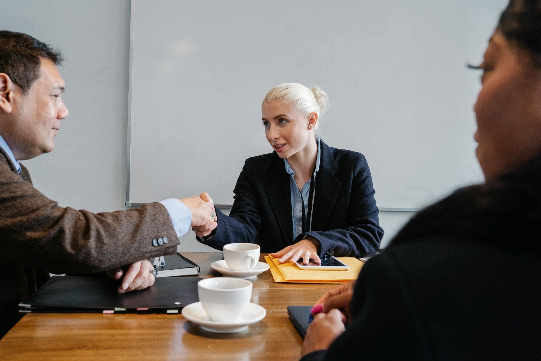 Group of diverse coworkers in formal suits shaking hands after successful business deal in office