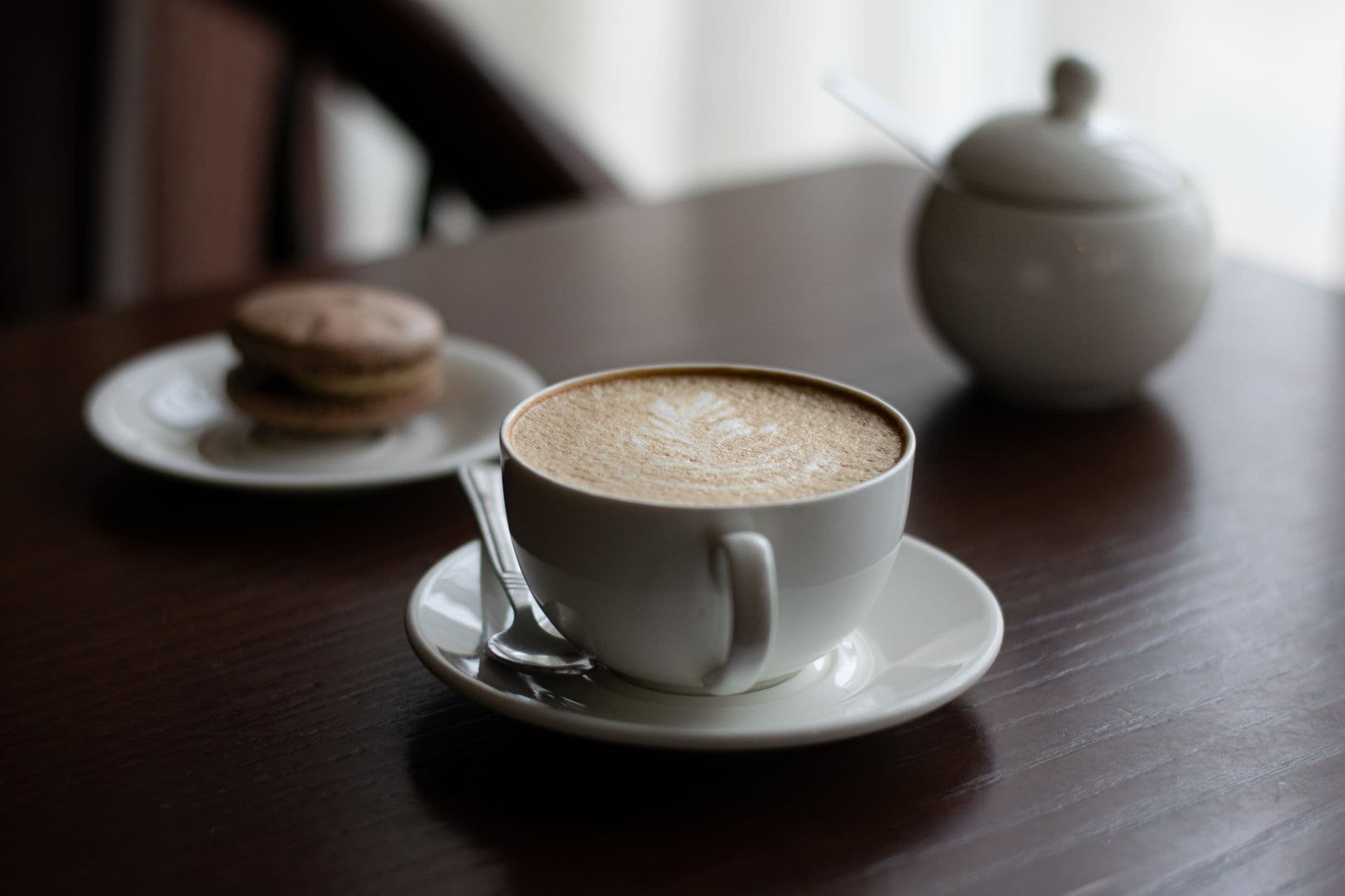 Serene composition featuring a cappuccino and macarons on a wooden table, exuding a cozy ambiance.