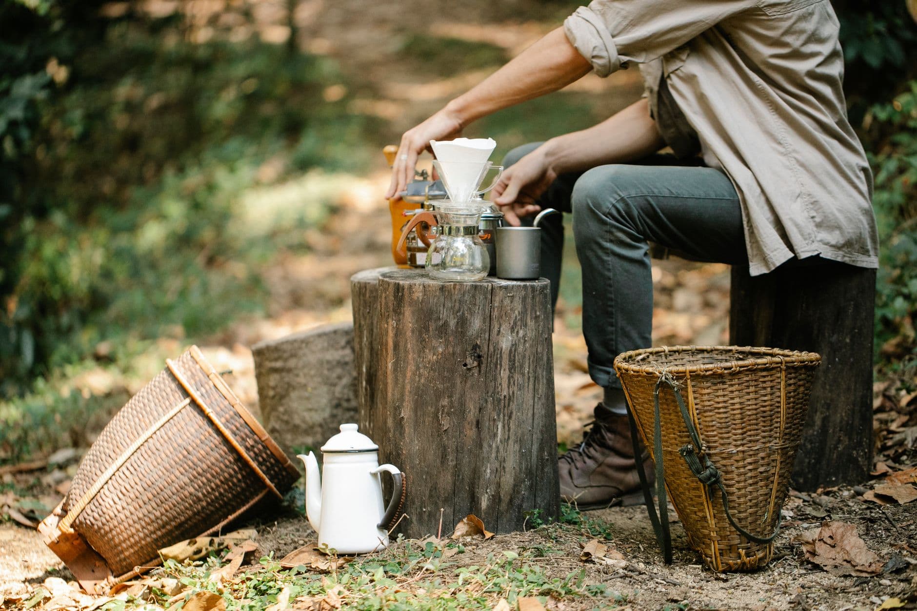 Side view of crop anonymous male harvester with manual coffee grinder and pour over maker preparing hot beverage on pathway